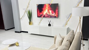 Ein modernes Wohnzimmer mit einer Couch, einem Couchtisch, einem an der Wand montierten Fernseher und einer Lampe.