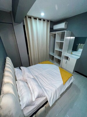 Ein modernes Schlafzimmer mit einem Bett, einem Kleiderschrank und einer integrierten Klimaanlage.