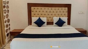 A bedroom with a tufted headboard, two pillows, a bedspread, and a nightstand. - Kakatiya Resort (Govindaraopet)