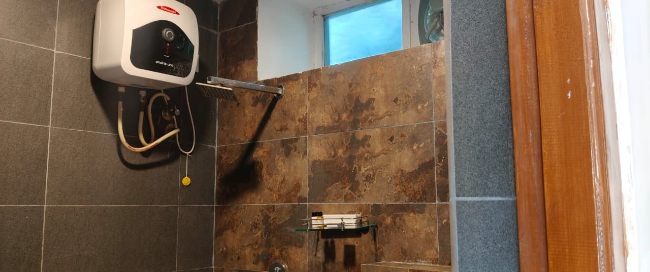 A bathroom with a hand dryer, a towel rack, and a showerhead.