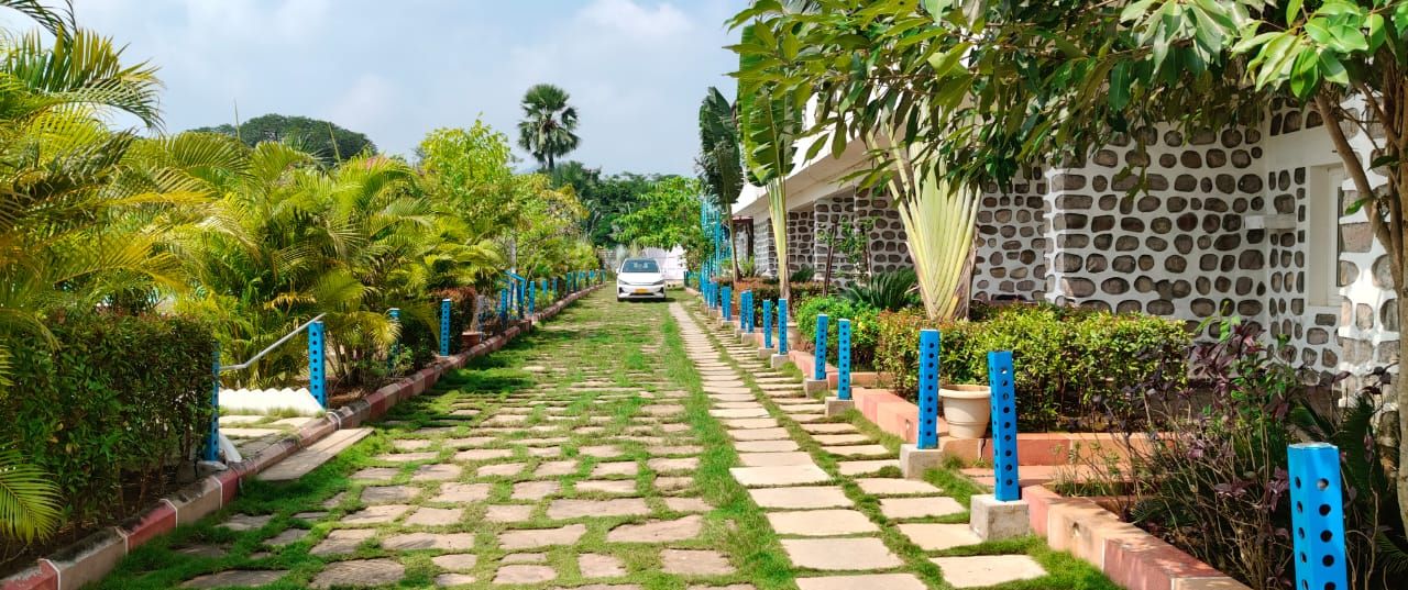A pathway leading to a building with a stone wall and blue bollards.