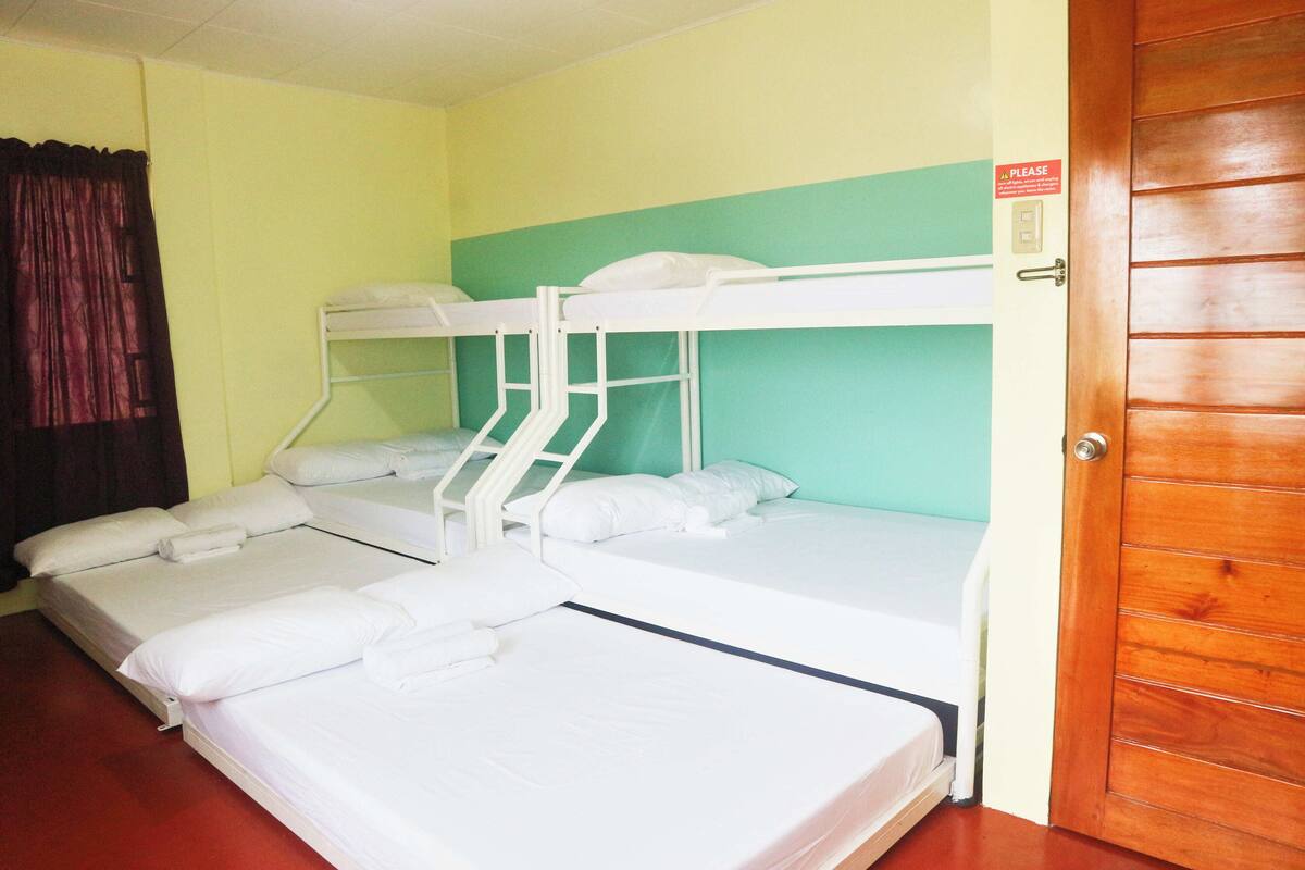 A room with bunk beds, a wooden door, and a sign on the wall.