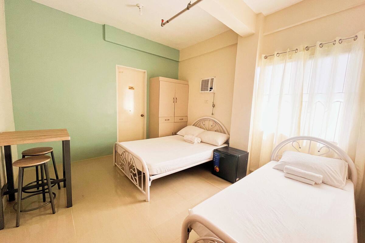 A bedroom with two beds, a desk, and a wardrobe.