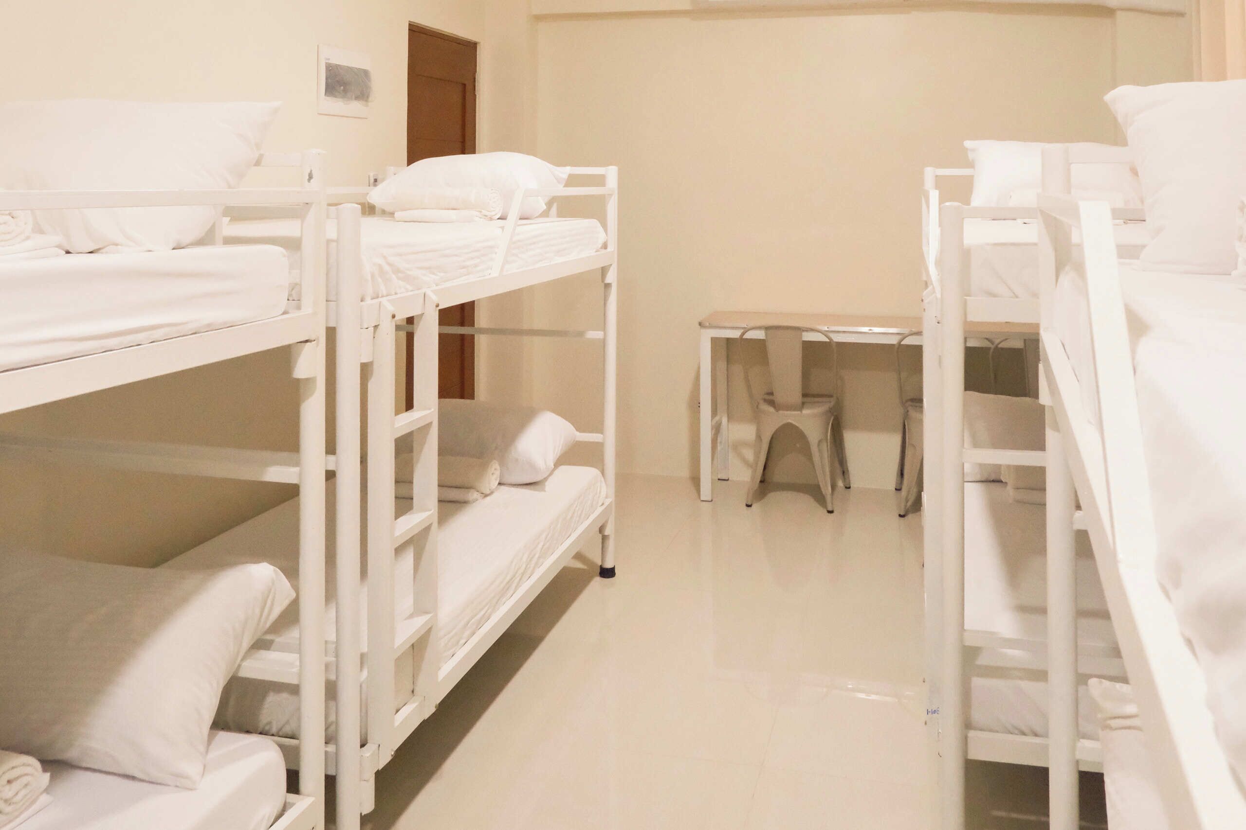 A clean, well-lit room with bunk beds and a small desk.