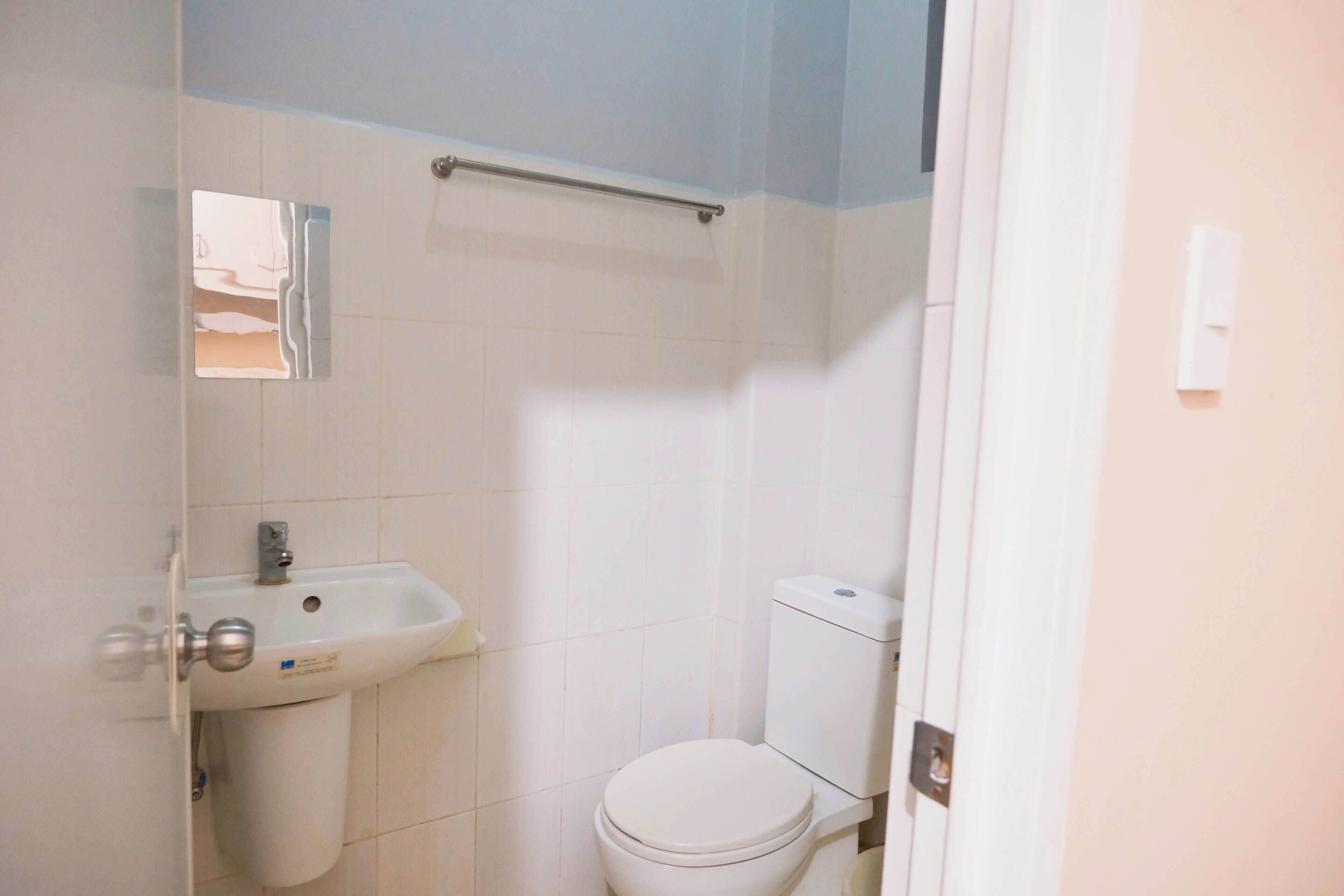 Un baño con lavamanos, inodoro y espejo blancos.
