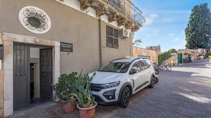 Ein weißer SUV vor einem Gebäude mit dem Schild 'Domus Elia Apartment Taormina'.