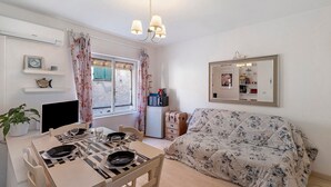 A room with a dining table set for two, a sofa, a small TV, a microwave, a mirror, and a potted plant. - Apartment 'La Casa di Iris with Parking Space', Wi-Fi and Air Conditioning (Diano Marina)