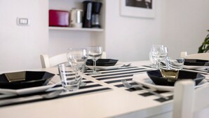 A dining table set with black plates, clear glasses, and a striped placemat. - Apartment 'La Casa di Iris with Parking Space', Wi-Fi and Air Conditioning (Diano Marina)