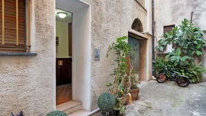 A narrow alleyway with a building entrance, a motorcycle, and potted plants. - Apartment 'La Casa di Iris with Parking Space', Wi-Fi and Air Conditioning (Diano Marina)