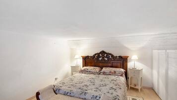 Une chambre à coucher avec un lit en bois, deux tables de chevet, une commode et une armoire.
