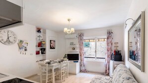 A modern kitchen with a dining area, a sofa, and a large window with curtains. - Apartment 'La Casa di Iris with Parking Space', Wi-Fi and Air Conditioning (Diano Marina)