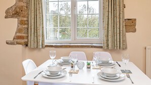 A dining table set for four with white plates, bowls, and glasses, positioned in front of a window with curtains. - Scosthrop - Bridge End Mill By Guestz (Settle)