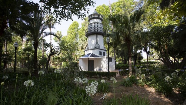 A white lighthouse with a black top, surrounded by lush greenery and flowering plants. - La Pergola 1D - Interior Studio with Terrace (Castellón)