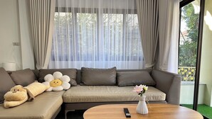 Una sala moderna con un sofá, una mesa de centro y una ventana con cortinas ligeras.