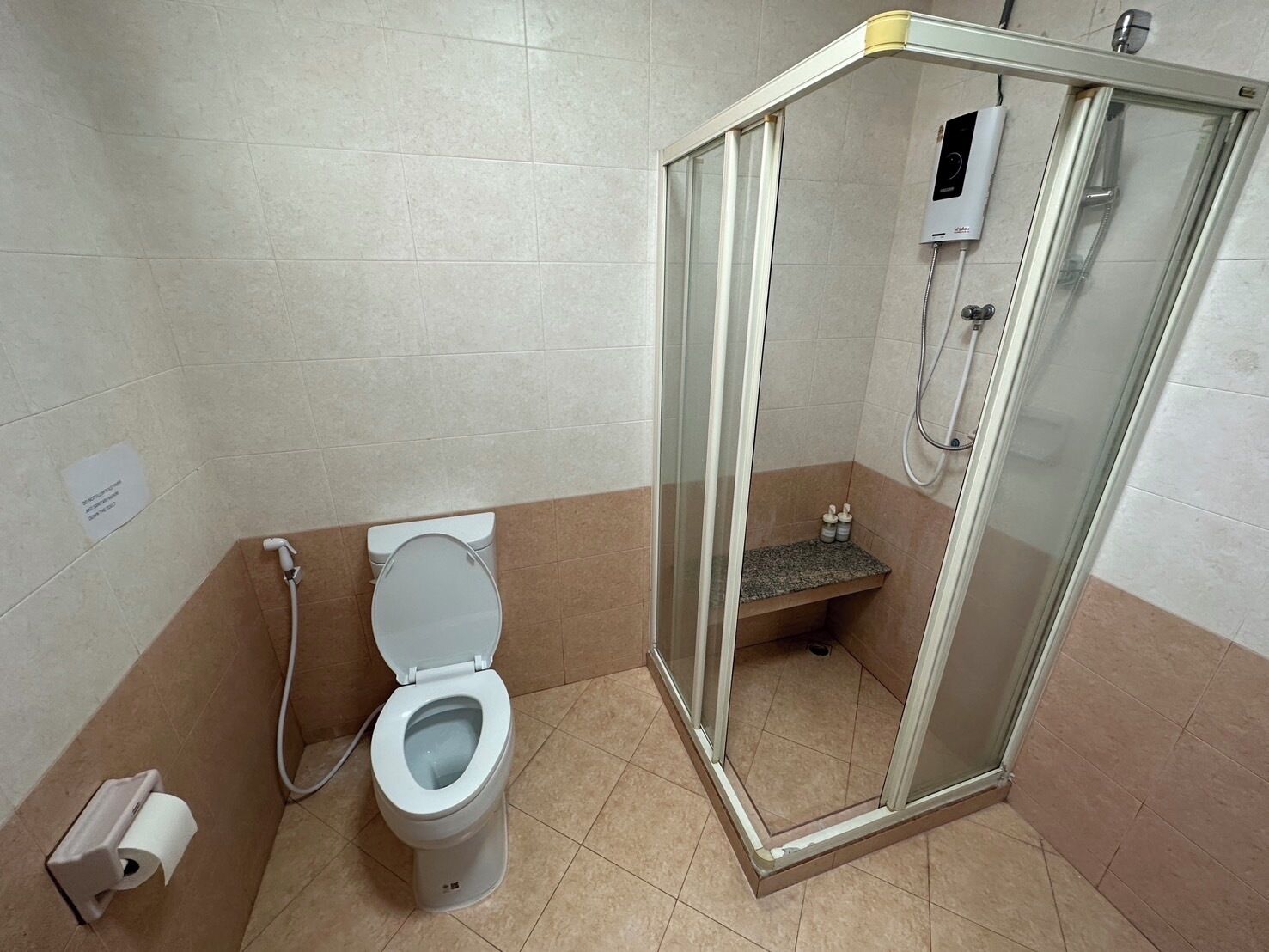 A bathroom with a toilet, a shower enclosure, and a toilet paper holder.