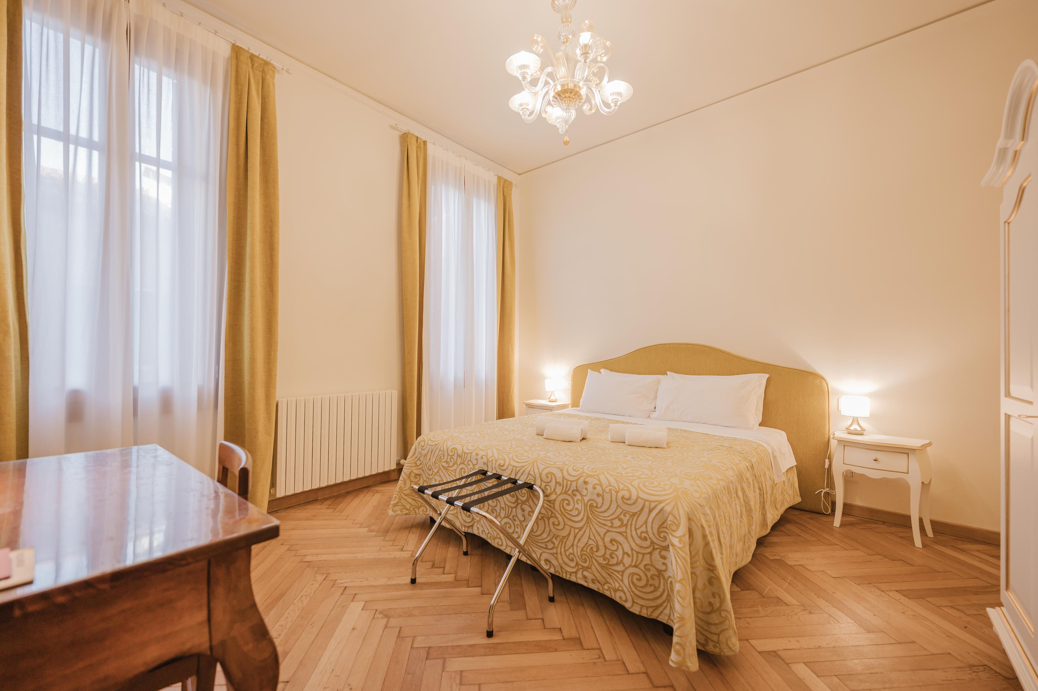 Una habitació d'hotel amb un llit, una tauleta de nit, una taula i una cadira.