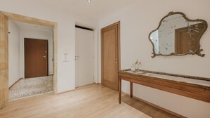 A hallway with wooden flooring, a wooden door, and a mirror on the wall. - Santo Stefano Palace  (Venice)