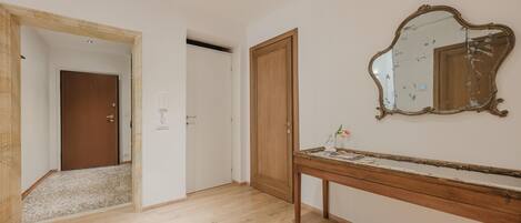 Ein Flur mit Holzboden, einer Holztür und einem Spiegel an der Wand.
