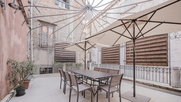 An outdoor patio with a table and chairs, surrounded by potted plants and umbrellas. - Santo Stefano Palace  (Venice)