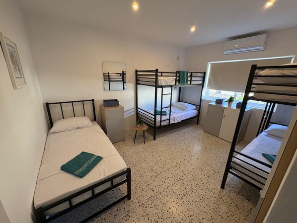 A dormitory room with bunk beds, a small desk, a chair, and a window. - Windmill Hostel (St. Julian's)