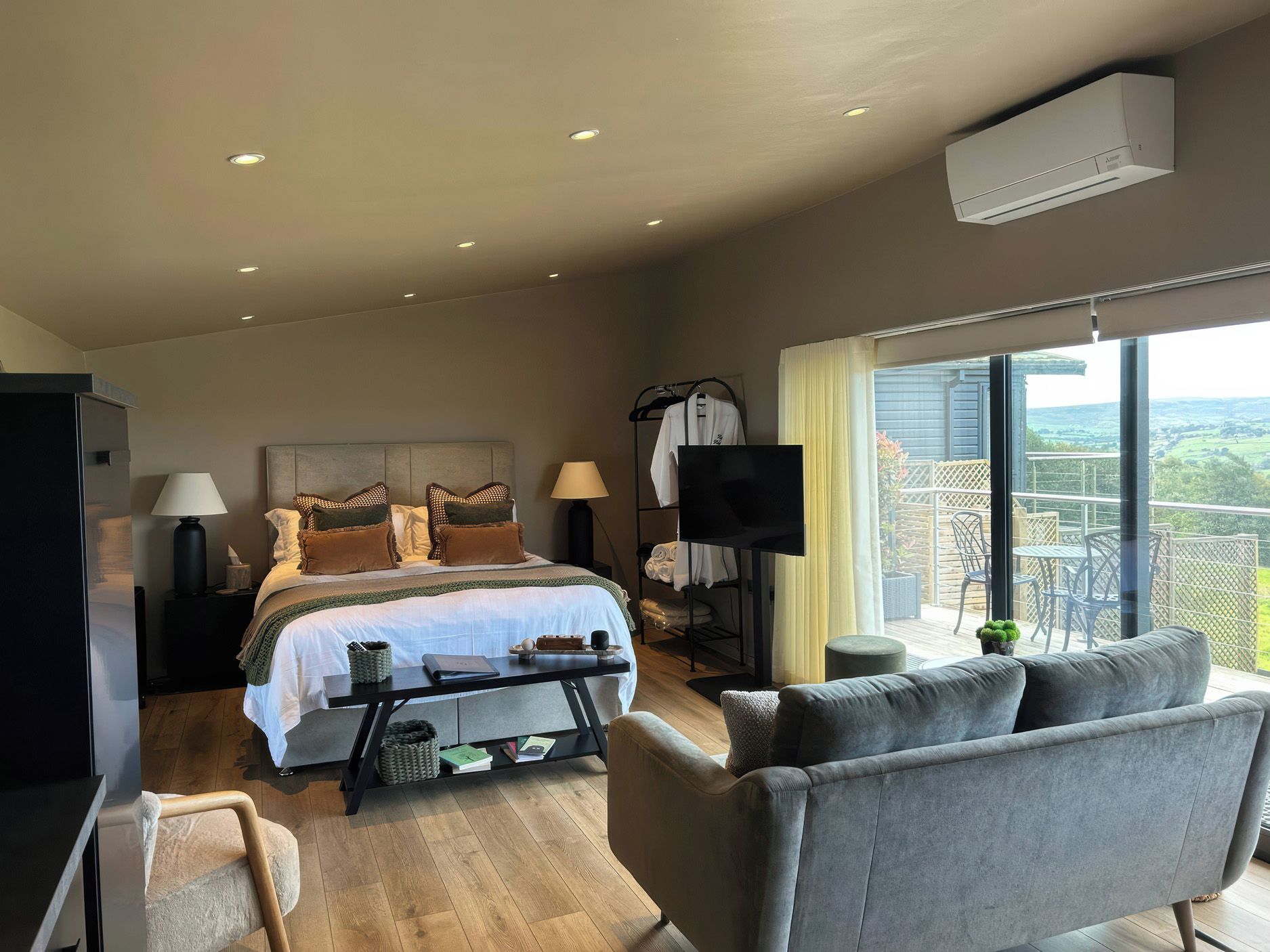 Una habitación de hotel moderna con una cama grande, un televisor de pantalla plana, un sofá y un balcón con vistas.
