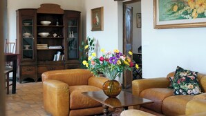 Una sala de estar con sofás de cuero, un mueble de madera y un jarrón de flores sobre una mesa.