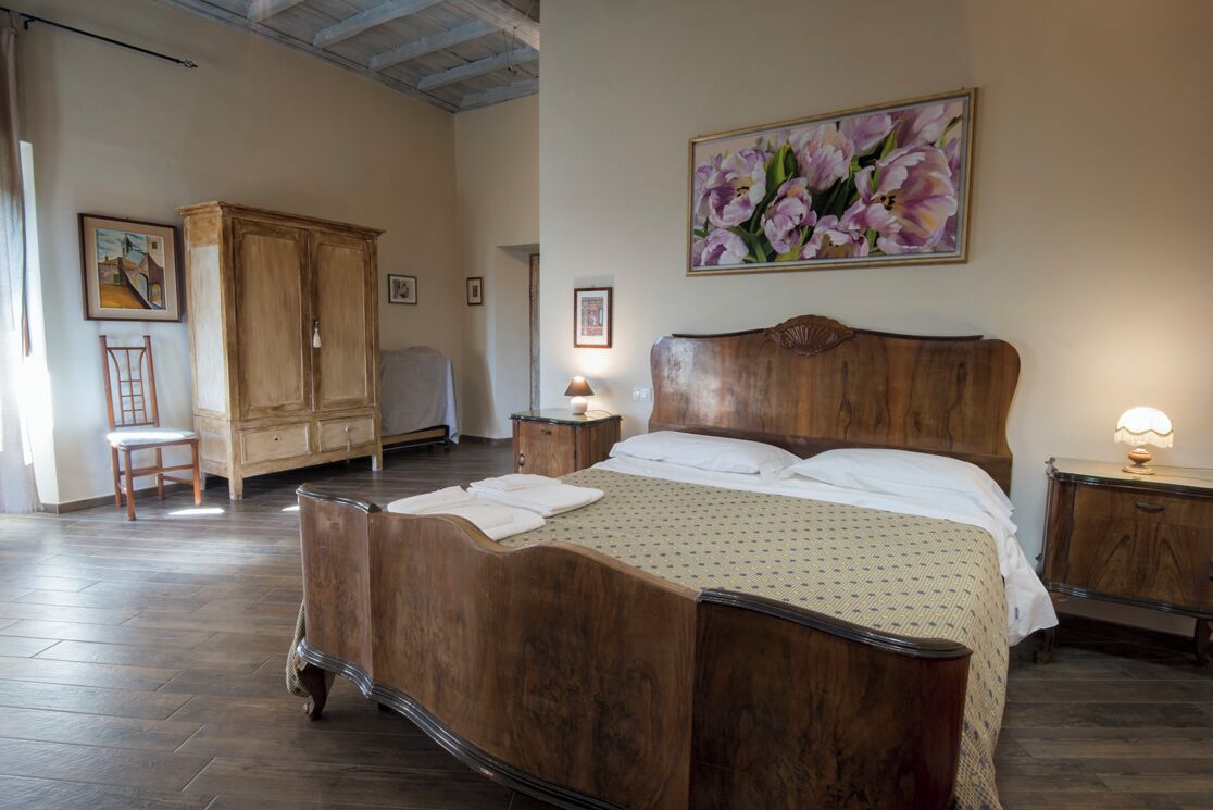 Un dormitorio con una cama y un armario de madera, una silla y un cuadro en la pared.