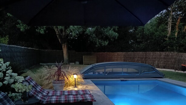 A poolside area with lounge chairs and a table under an umbrella.