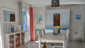 A dining area with a table and chairs, a cabinet with glass doors, and a ceiling light fixture.