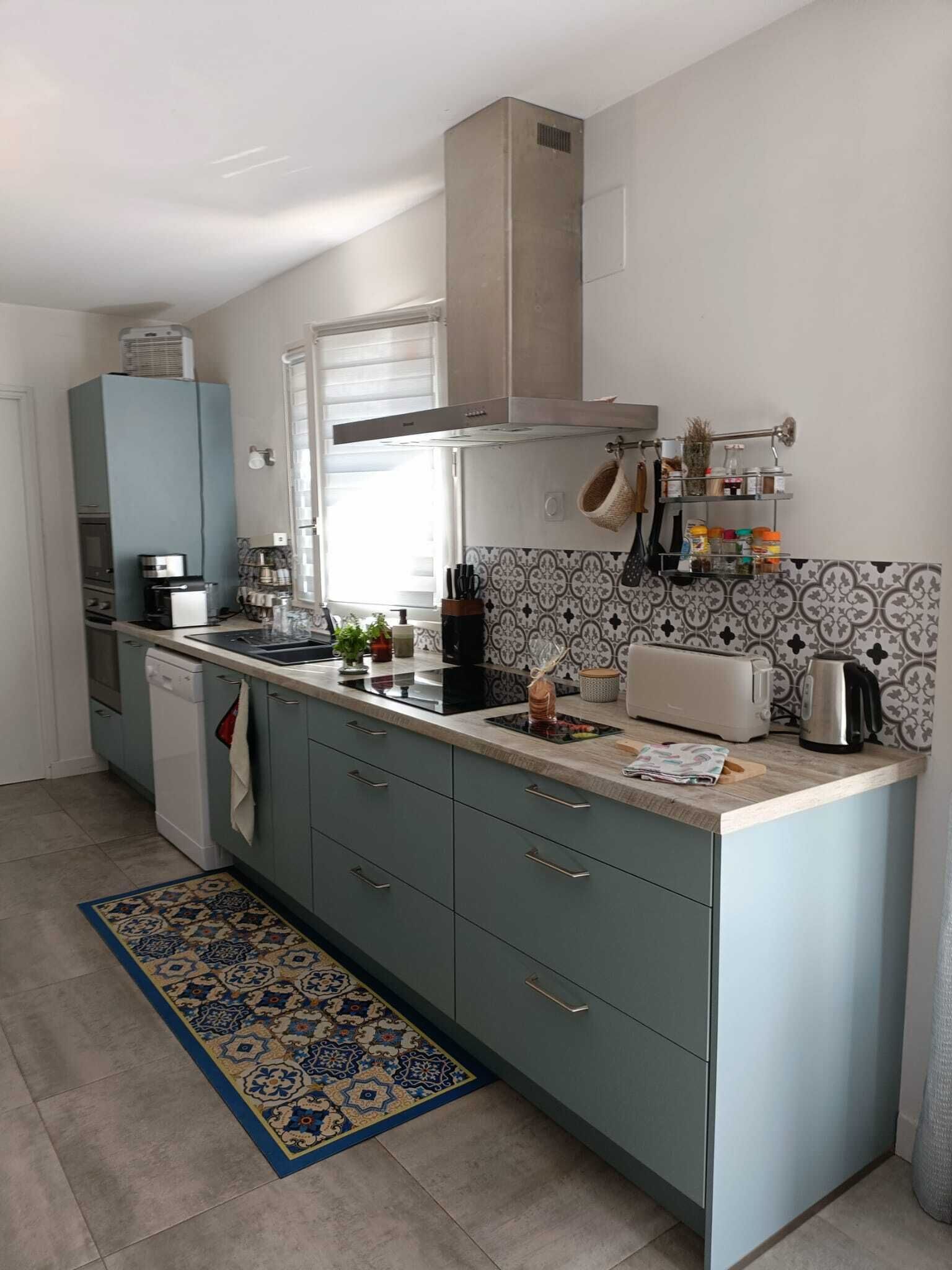 A modern kitchen with grey cabinets, a built-in oven, and a coffee maker.