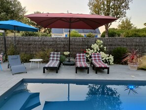 A poolside area with lounge chairs and umbrellas, a small table, and a potted plant. - House with heated pool (LAUZACH)