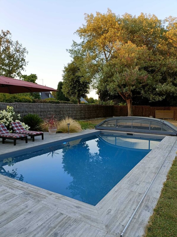 A rectangular swimming pool with a wooden deck, two lounge chairs, and a large tree in the background. - House with heated pool (LAUZACH)
