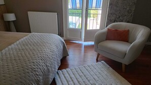 A bedroom with a bed, a chair, a radiator, and a view through a door.
