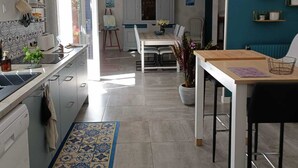 A modern kitchen with a dining area, featuring a large island, white cabinetry, and a blue accent wall.