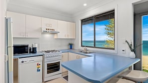 A modern kitchen with white cabinets, a blue countertop, a gas stove, a microwave, and a dishwasher. - Forresters Dunes - Downstairs (Forresters Beach)