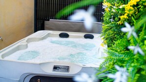 A hot tub with a control panel, surrounded by lush greenery and a wooden deck. - Éveil en blanc - Private Jacuzzi & cotton comfort (Verdun)