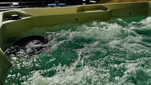 Un bain à remous rempli d’eau, avec une balustrade et un ciel dégagé en arrière-plan.