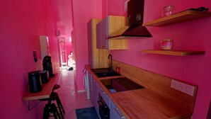 Une cuisine moderne avec des meubles en bois, un plan de travail noir et un évier. Deux étagères sont fixées au mur au-dessus du plan de travail.