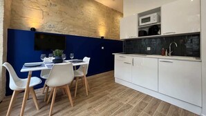 Una cocina moderna con armarios blancos, un microondas y un fregadero. Hay una zona de comedor con una mesa y sillas.