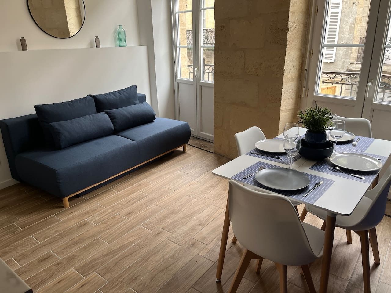 Een moderne woonruimte met een bank, eettafel, stoelen en een potplant.