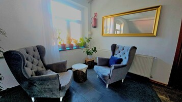 Una habitación con dos sillones, una mesita redonda y una planta en maceta.