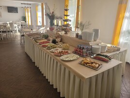 Montaje de bufé con diversas opciones de comida y una larga mesa cubierta con un paño color beige.