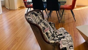 A dining area with a table and chairs, a guitar with magazine covers, and a view of buildings through large windows. - Elegance et confort au centre de Bordeaux (Bordeaux)