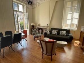 Un salon spacieux avec une table à manger en verre, des chaises modernes, un canapé agrémenté de coussins à motifs et une cheminée.