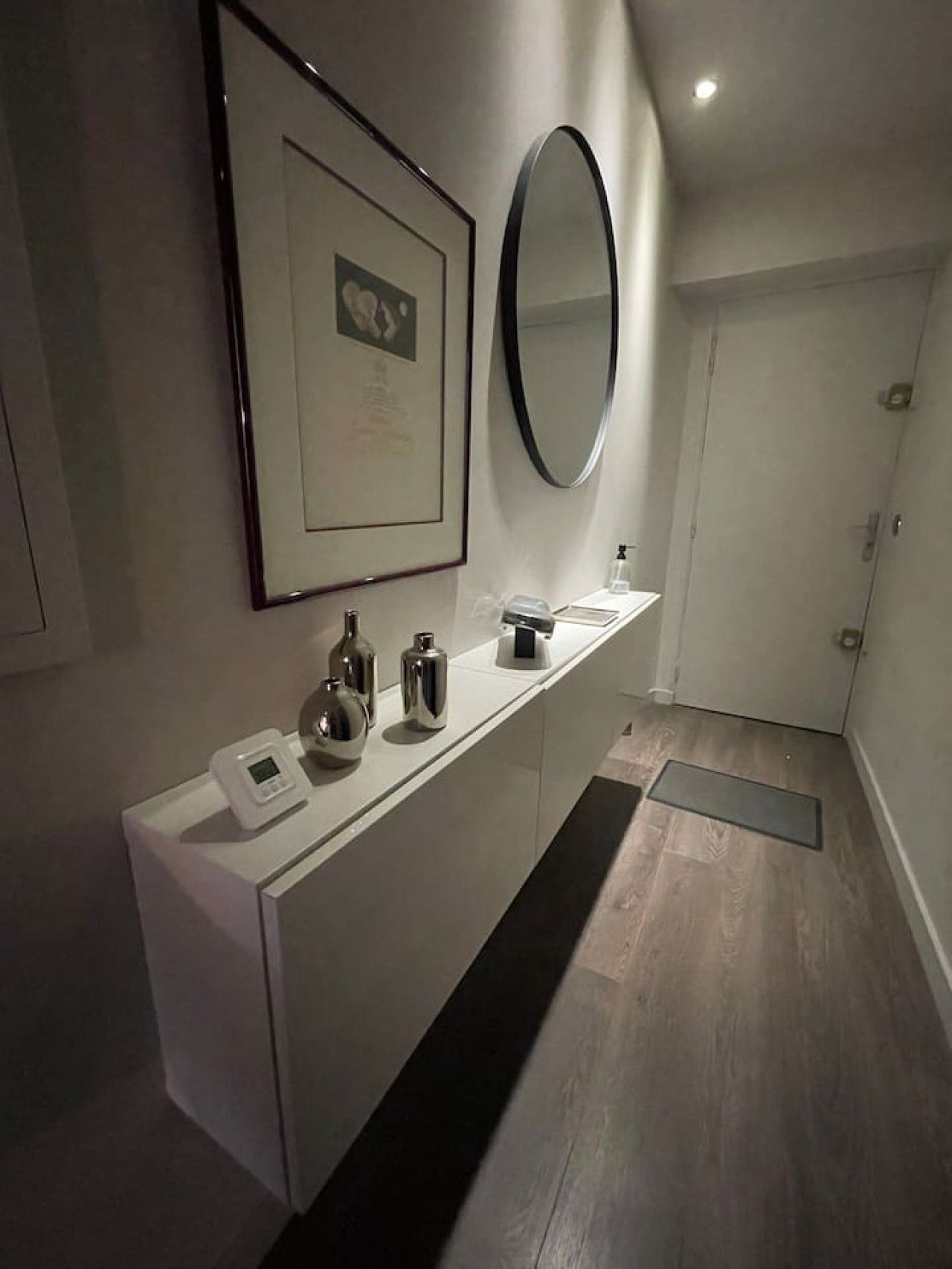 Ein modernes Badezimmer mit Waschtisch, Spiegel und einem gerahmten Bild an der Wand.