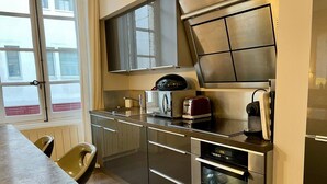 Una cocina moderna con electrodomésticos de acero inoxidable, horno empotrado y ventana con vistas a la calle.