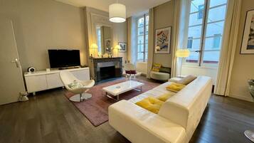 Ein modernes Wohnzimmer mit einer Couch, einem Sessel und einem Flachbildfernseher.