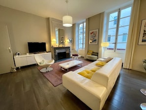 Ein modernes Wohnzimmer mit einer Couch, einem Sessel und einem Flachbildfernseher.