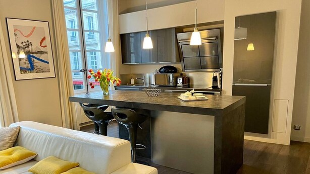 Una cocina moderna con una isla central, iluminación colgante y vistas al exterior.