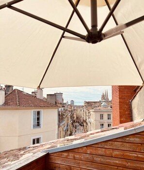 A rooftop terrace with a view of a cityscape, including buildings and a church spire.
